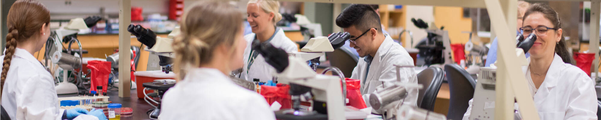 Students in a classroom lab looking through microscopes